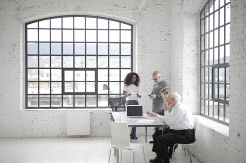 Four colleagues talking around a shared table in a bright office